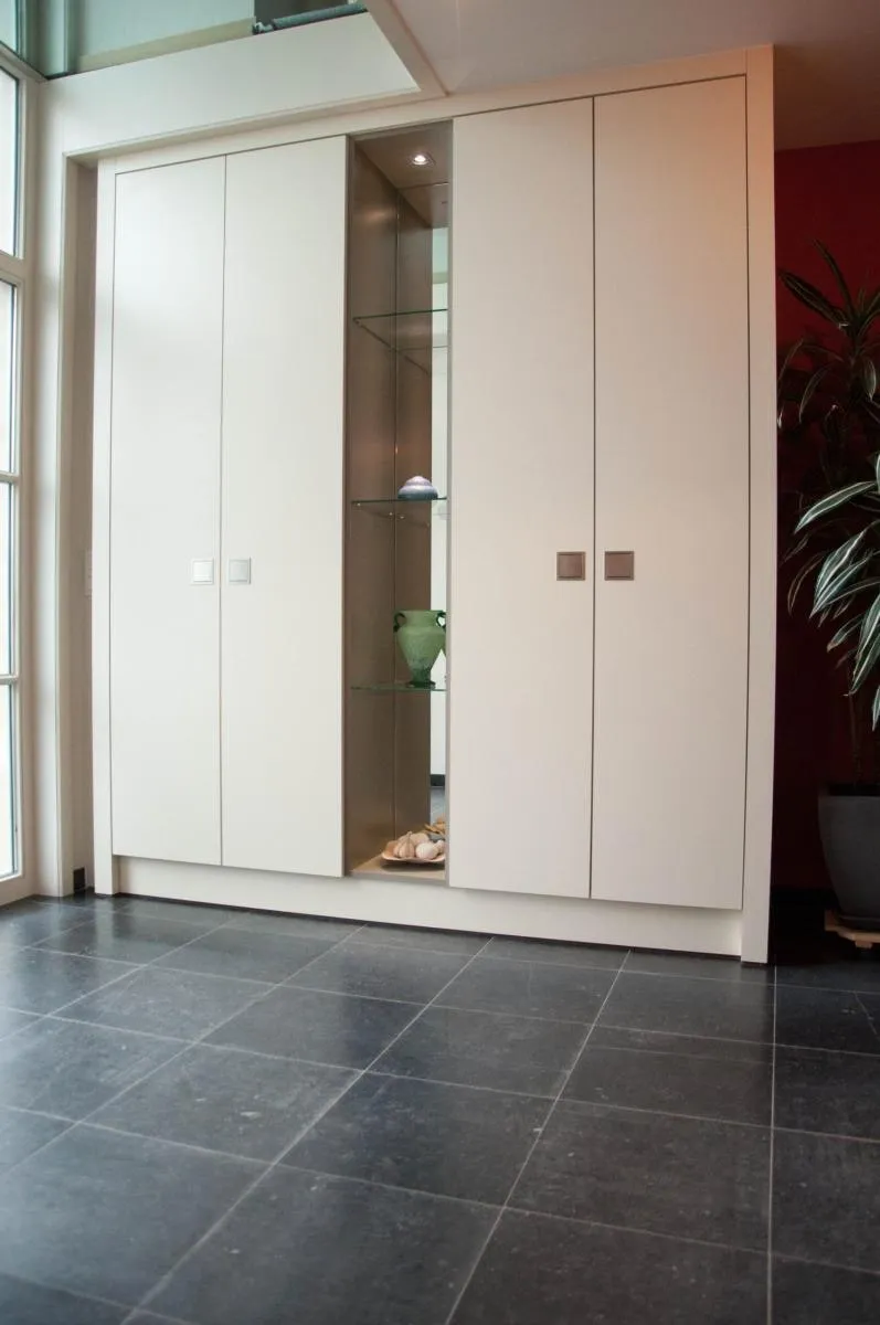 Hoge witte kastenwand met glazen vitrine in het midden