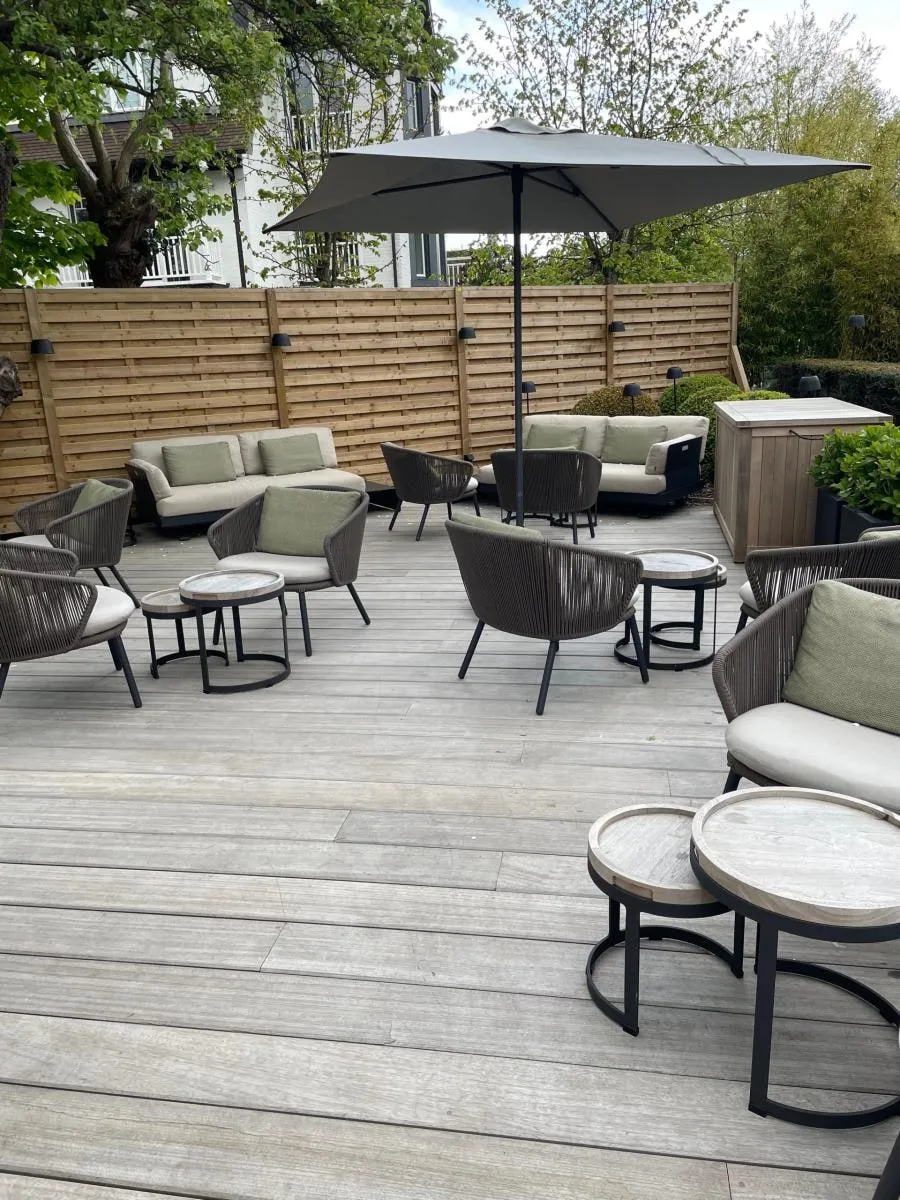 Terras in houten planken met loungemeubilair en een parasol