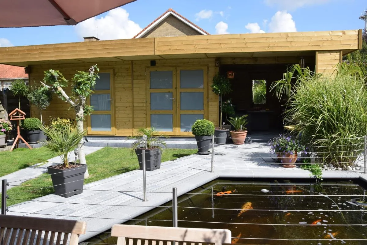 Houten tuinhuis met overdekte zone, aan een terras met vijver
